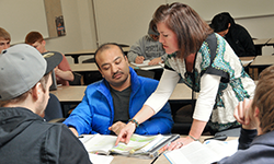 Instructor pointing to a textbook with PCC students.